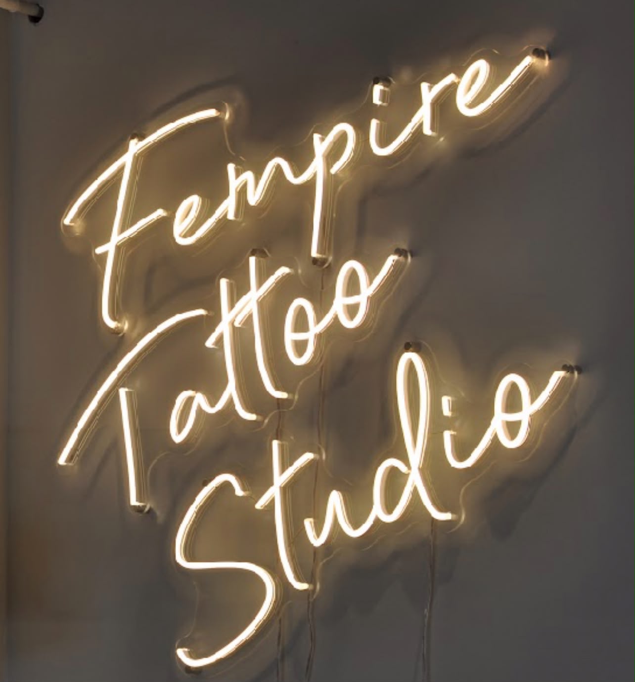 Neonbord met de naam Fempire Tattoo Studio in de studio